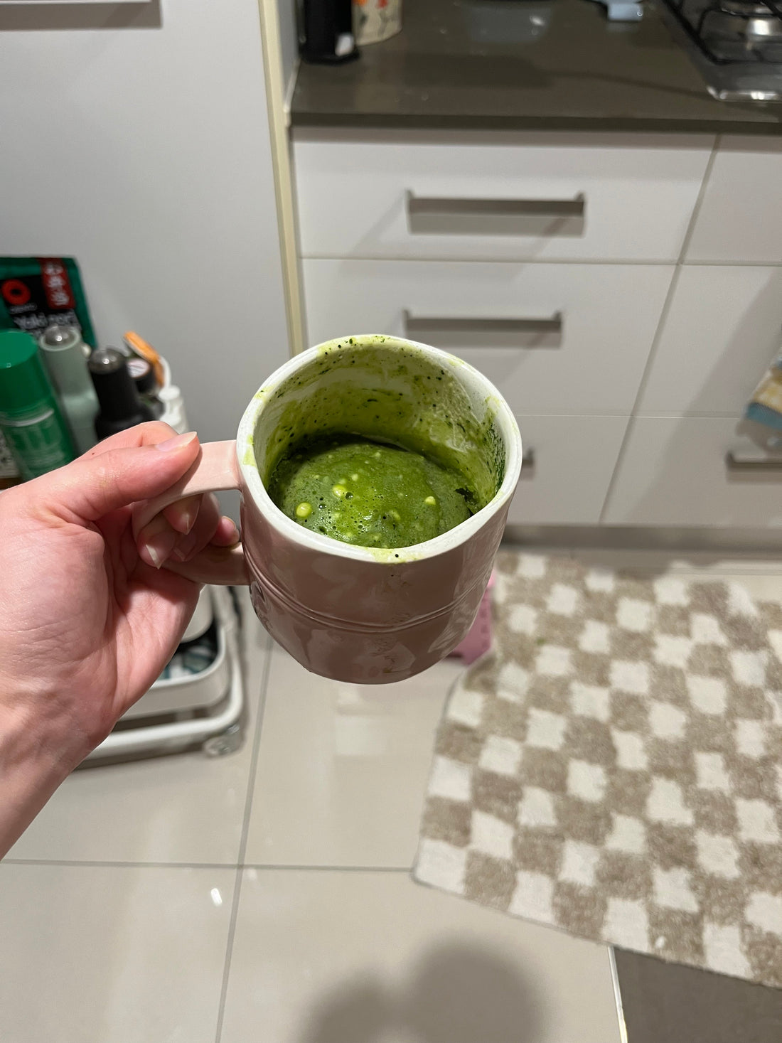 holding pink mug with matcha mug cake inside with white chocolate chips on top